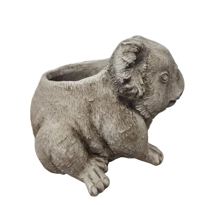 A realistic gray koala figurine sitting on a light wood surface against a plain light gray wall.